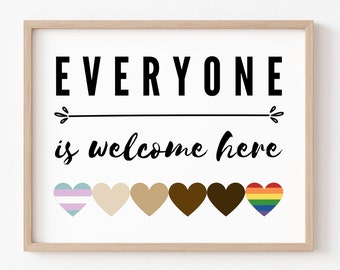 May include: A framed print with the text "EVERYONE is welcome here" in black lettering.  Below the text are six hearts in a row, each a different color: light blue and pink, beige, brown, dark brown, and rainbow.