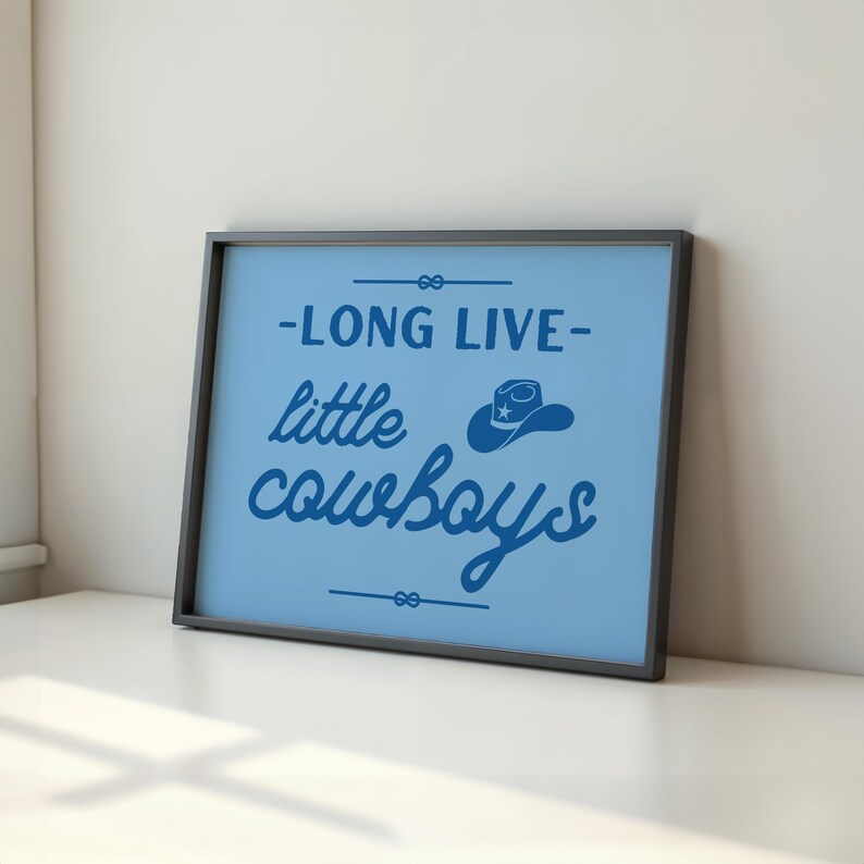 May include: A blue framed print with the text "Long Live Little Cowboys" in a blue script font. A blue cowboy hat with a white star is above the word "cowboys".