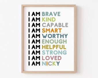 May include: A framed print with the text "I AM" followed by a list of positive affirmations in different colors, including "BRAVE", "KIND", "CAPABLE", "SMART", "WORTHY", "ENOUGH", "HELPFUL", "STRONG", "LOVED", and "NICKY".