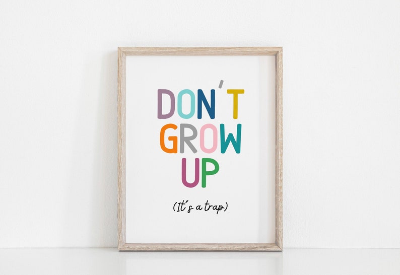 May include: A framed print with the text "DON'T GROW UP (It's a trap)" in colorful letters. The letters are in different colors, including purple, blue, teal, orange, gray, pink, and green.