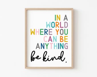 May include: A colorful typography print with the text "In a world where you can be anything be kind."