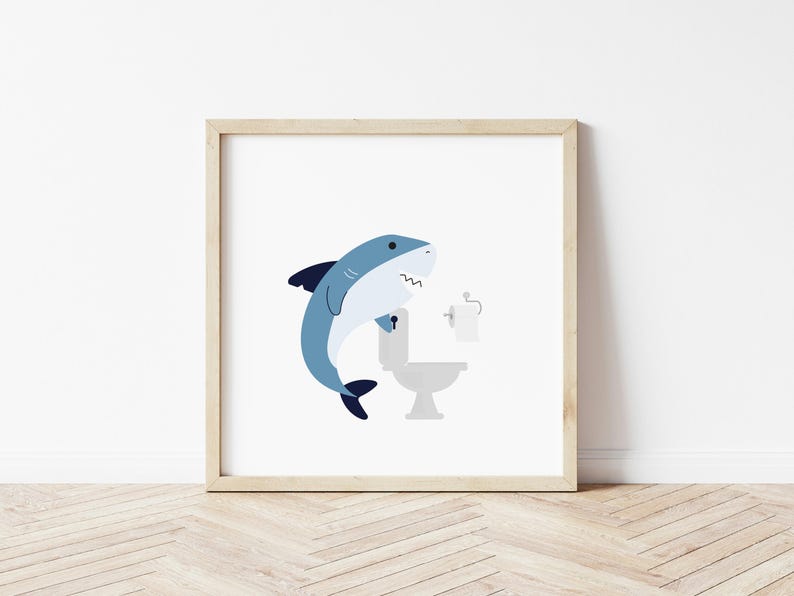 May include: A blue shark cartoon illustration with an open mouth, holding onto a white toilet with a roll of toilet paper on the holder. The image is framed in a light wood frame.