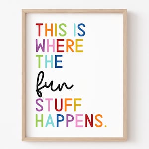 May include: A framed print with the text "This is where the fun stuff happens." in a rainbow of colors. The words "fun" and "stuff" are in black.