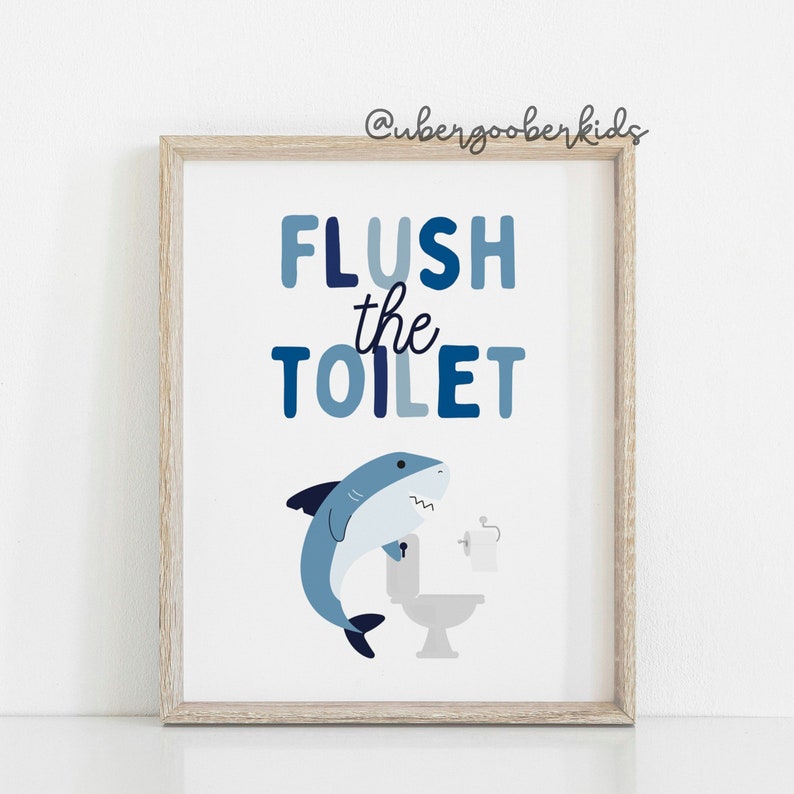 May include: A blue and white bathroom sign with a shark illustration and the text "FLUSH the TOILET".