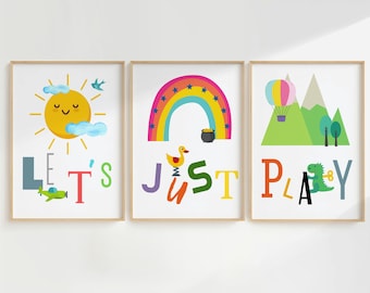 May include: Three framed prints with a colorful theme. The first print features a yellow sun with a smiling face, clouds, and the words "Let's". The second print features a rainbow with stars, a pot of gold, a yellow duck on a spring, and the words "Just". The third print features a hot air balloon, mountains, a green dinosaur, and the words "Play".