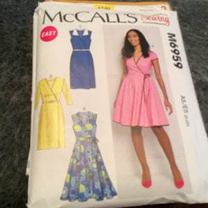 Może przedstawiać: Wzór szycia McCall's M6959 na sukienkę z zakładkami. Wzór zawiera cztery różne style: niebieską sukienkę z kołnierzykiem, żółtą sukienkę z zakładkami, niebiesko-zieloną sukienkę z zakładkami i różową sukienkę z zakładkami. Wzór jest oznaczony jako "Łatwy" i zawiera rozmiary 6-14.