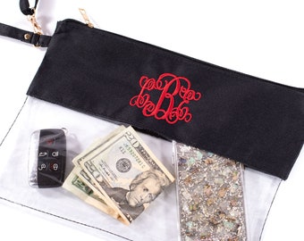 May include: A clear plastic crossbody bag with a black fabric flap. The flap has a red embroidered monogram. The bag is open and shows a cell phone, cash, and a car key inside.