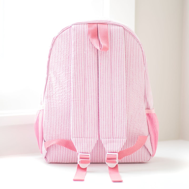 May include: Pink striped backpack with pink straps and white buckles.