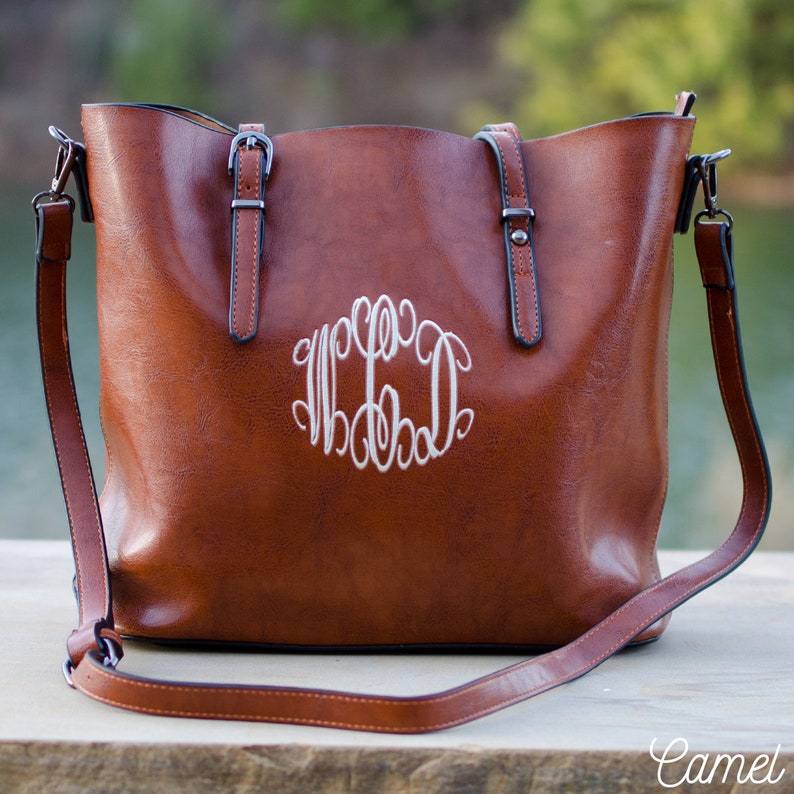 Pu&ograve; includere: Una borsa tote color cammello con un monogramma bianco. La borsa ha due manici e una tracolla staccabile. La borsa &egrave; realizzata in un materiale liscio e ha finiture color argento.