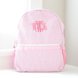 May include: Pink and white striped backpack with a pink monogrammed initial "W" on the front.