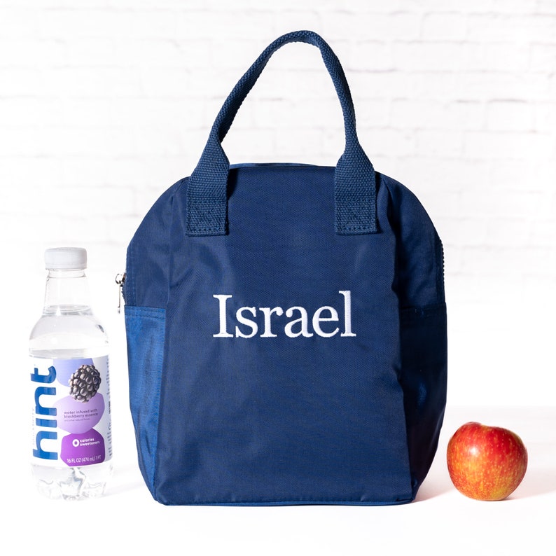 May include: A navy blue lunch bag with a zippered pocket and a white embroidered name "Israel".