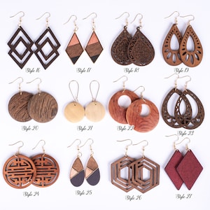 May include: Assortment of 12 pairs of wooden earrings in various styles and colors. The earrings are made of wood and have different shapes, including circles, squares, diamonds, and teardrops. Some earrings are plain wood, while others have intricate designs or are painted with different colors.