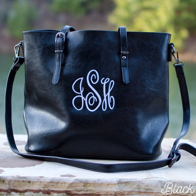 Pu&ograve; includere: Borsa tote nera con monogramma bianco. La borsa ha una tracolla e due manici. La borsa &egrave; realizzata in un materiale liscio e ha finiture color argento. La parola "Black" si trova in basso a destra.