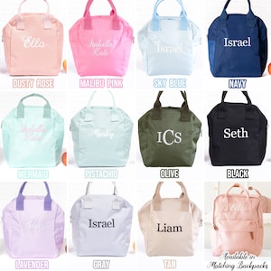 May include: Twelve different colored lunch bags with various names embroidered on them. The bags are made of canvas and have a zipper closure. The colors include dusty rose, malibu pink, sky blue, navy, mermaid, pistachio, olive, black, lavender, gray, tan, and pink.