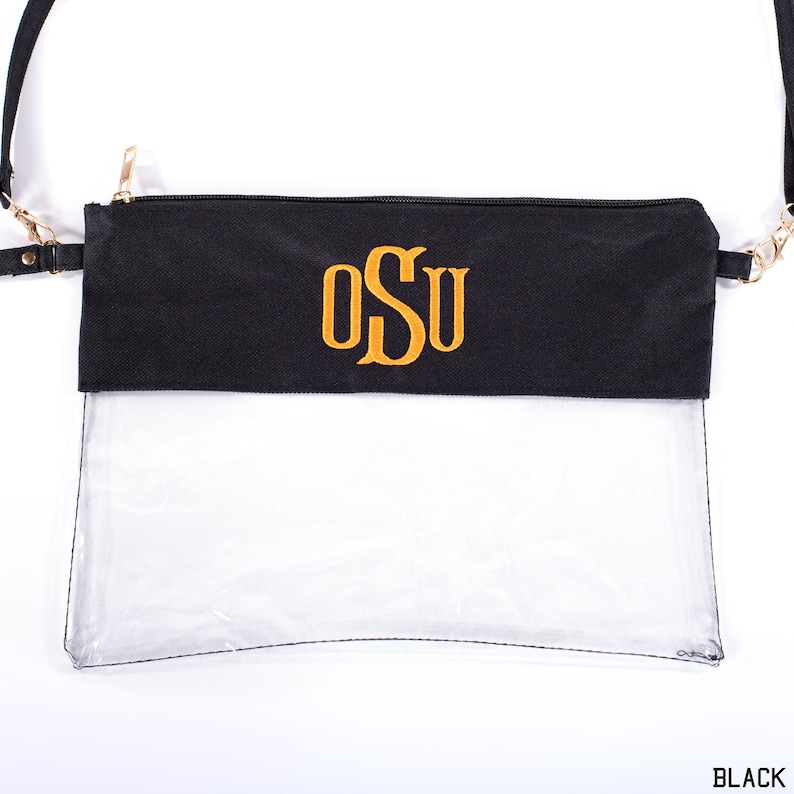 May include: Black clear crossbody bag with a gold chain strap and a black fabric flap with the monogram "OSU" embroidered in gold.