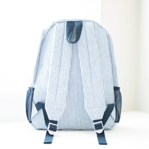 May include: A blue and white striped backpack with adjustable straps and mesh side pockets.