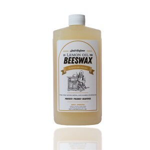 Może przedstawiać: Przezroczysta plastikowa butelka z woskiem pszczelim z olejkiem cytrynowym do polerowania mebli z białą nakrętką. Etykieta zawiera tekst Amish Craftsmen, Lemon Oil, Beeswax, Furniture Polish oraz ilustrację osoby przy pracy.