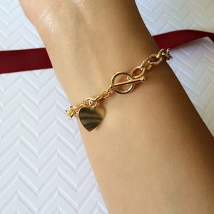 Peut inclure: Un bracelet en chaîne dorée avec un pendentif en forme de cœur et un fermoir à bascule.