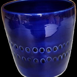 May include: A deep blue ceramic planter with a textured design of two rows of small circles around the middle.
