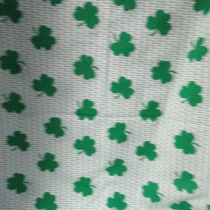 May include: White fabric with a repeating pattern of green shamrocks.