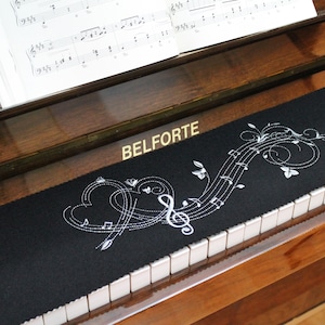 May include: Black piano keyboard with a black and white embroidered piano key cover with the words "BELFORTE" and musical notes and hearts.