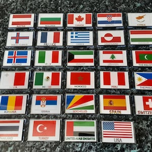 May include: A collection of thirty rectangular magnets featuring various national flags, each labelled with its corresponding country name in black text. The flags include Austria, Bulgaria, Canada, Croatia, Cyprus, Faroe Islands, France, Greece, Greenland, Hungary, Iceland, Italy, Kuwait, Lebanon, Maldives, Malta, Mexico, Morocco, Peru, Philippines, Romania, Serbia, Seychelles, Spain, Switzerland, Thailand, Turkey, United Arab Emirates, and the USA.