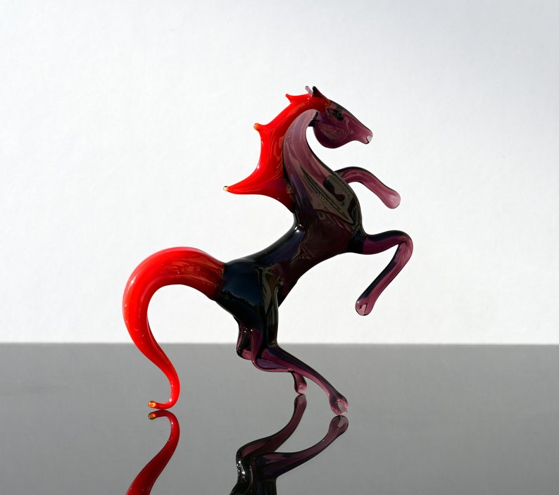 Peut inclure: Sculpture en verre d'un cheval cabr&eacute; avec une crini&egrave;re et une queue rouges. Le cheval est en verre violet fonc&eacute; et pr&eacute;sente un design d&eacute;taill&eacute;.