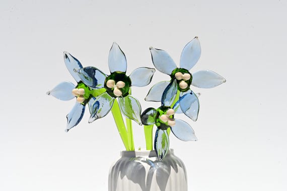 A flame-worked borosilicate glass forget-me-not bloom — a botanically detailed forever flower sculpted by hand that will never wilt.