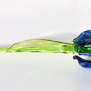 May include: A glass sculpture of a blue iris flower with a green stem.