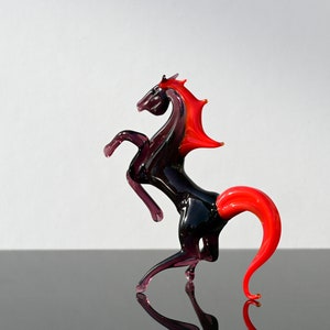 Peut inclure: Une figurine de cheval en verre noir avec une crini&egrave;re et une queue rouges. Le cheval se dresse sur ses pattes arri&egrave;re.