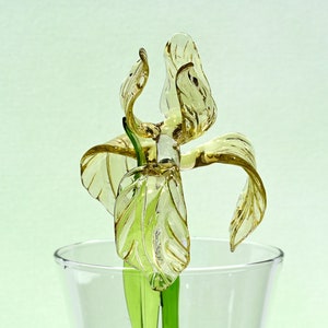 May include: A glass sculpture of a yellow iris flower with green stem in a clear glass vase.