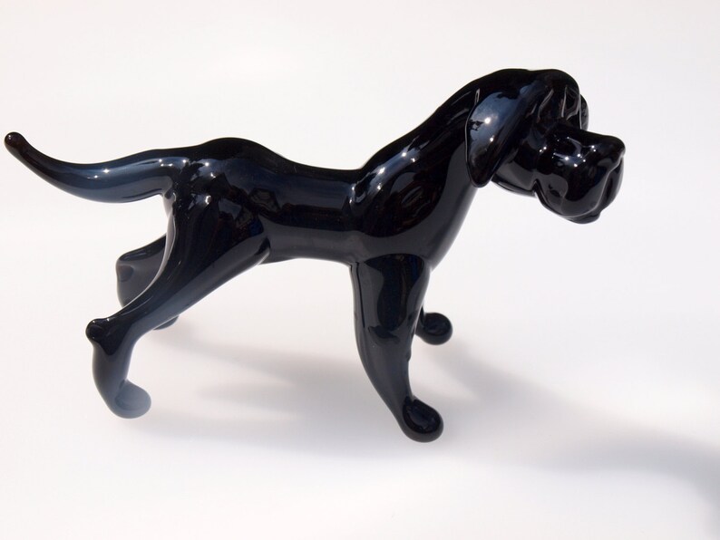 May include: A black glass sculpture of a dog in a walking pose. The dog has a long snout and a short tail.