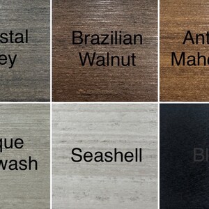 May include: A collection of six wood stain samples, each labeled with a color name. Colors include Coastal Grey, Brazilian Walnut, Antique Mahogany, Antique Whitewash, Seashell, and Black. The wood grain is visible in each sample.