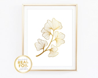 May include: Gold foil art print featuring a ginkgo leaf design. The artwork is framed in a gold-colored frame and set against a white background. The print includes the text "MULTIPLE REAL FOIL COLORS AVAILABLE".