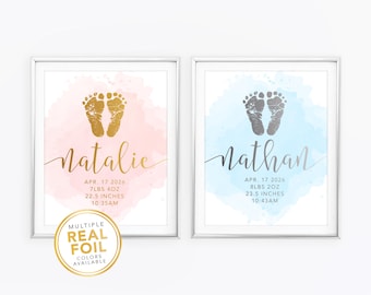 Puede incluir: Dos impresiones enmarcadas con huellas de bebé. Una presenta huellas doradas, el nombre "Natalie" y detalles del nacimiento sobre un fondo de acuarela rosa. La otra tiene huellas plateadas, el nombre "Nathan" y detalles del nacimiento sobre un fondo de acuarela azul.