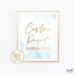 May include: Framed print with gold lettering reading "Custom Print IN REAL FOIL" on a white background with light blue watercolour accents. A gold sticker in the lower left corner says "MULTIPLE REAL FOIL COLORS AVAILABLE".