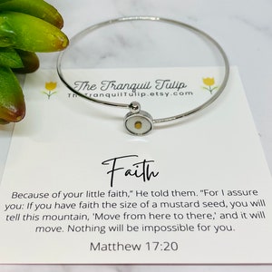 May include: A silver bangle bracelet with a small clear charm containing a mustard seed. The bracelet comes with a card that reads "Faith" and a Bible verse: "Because of your little faith," He told them. "For I assure you: If you have faith the size of a mustard seed, you will tell this mountain, 'Move from here to there,' and it will move. Nothing will be impossible for you." Matthew 17:20