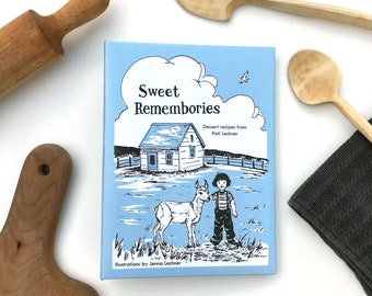 May include: A blue book with the title "Sweet Rememberies" and a subtitle "Dessert recipes from Patti Lechner". The book features an illustration of a small house, a deer, and a girl in a field.