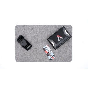May include: A gray felt mat with a black buckle, a black and silver card with the text "MC" and a small card with a red and white design.