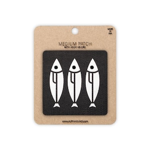 May include: A black square patch featuring three white stylized fish icons arranged horizontally. The patch is mounted on a tan cardboard backing labeled MEDIUM PATCH WITH HOOK VELCRO, MADE IN USA, and WWW.ALPINHOUND.COM at the bottom.