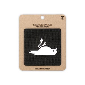 May include: A medium patch with hook and loop fastening, showing a white bird design on a black patch. The patch is on a cardboard backing with the text "MEDIUM PATCH WITH HOOK VELCRO" and "MADE IN USA". The website address www.alpinhound.com is also visible.