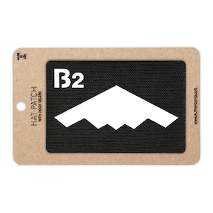 May include: A rectangular hat patch with hook and loop backing. The patch features a black background with a white graphic of a mountain range and the text "B2". The patch is on a cardboard backing with the text "HAT PATCH WITH HOOK VELCRO".