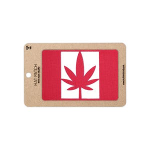 May include: A rectangular red and white hat patch with hook velcro backing, featuring a centered red cannabis leaf graphic. The patch is mounted on a tan cardboard display card with the text HAT PATCH WITH HOOK VELCRO and MADE IN USA.