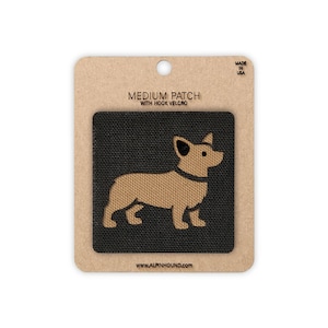 May include: A medium-sized patch with hook and loop fastener. The patch features a tan-coloured corgi dog silhouette on a black textured background. The patch is mounted on a cardboard backing with the text "MEDIUM PATCH WITH HOOK VELCRO" and "MADE IN USA".