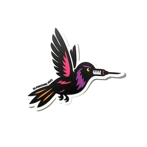 May include: A black, purple, and pink hummingbird sticker with a long, thin beak. The sticker has the text "ALPINHOUND 2023" on the left side of the bird.