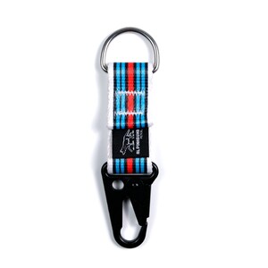Pu&ograve; includere: Un portachiavi a strisce bianche e blu con un moschettone nero. Il portachiavi ha un anello argentato e un patch con logo nero che dice "ALPINHOUND PET CO."