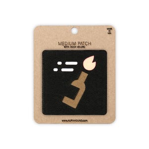 May include: A medium black patch with hook velcro. The patch features a stylized design of a bottle with a flame, and two horizontal lines. The text "MEDIUM PATCH WITH HOOK VELCRO" is above the patch. The website address is at the bottom.