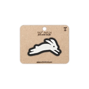 May include: A white rabbit patch with a black outline, measuring 1x2 inches, is displayed on a brown card. The card includes the text "1X2" PATCH WITH HOOK VELCRO" and "MADE IN USA". The website address www.alpinhound.com is also visible.