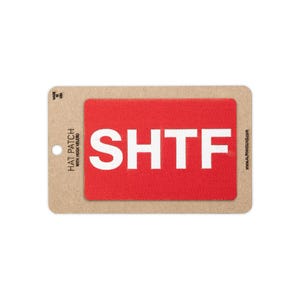 May include: A rectangular red hat patch with a hook backing featuring the white text SHTF. The patch is mounted on a tan cardboard display card that includes the text HAT PATCH WITH HOOK VELCRO, MADE IN USA, and ALPHAHOUND.COM printed on it.