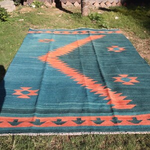 May include: A teal and orange geometric patterned rug with a fringe border. The rug has a southwestern design.